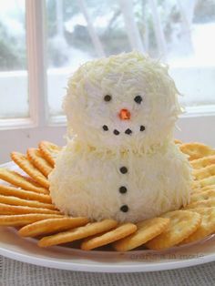 a white plate topped with crackers and a snowman made out of cheese