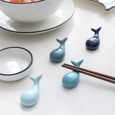 small ceramic whale figurines sitting next to chopsticks on a white table