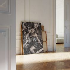 an empty room with a poster on the wall and wooden floors in front of it