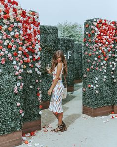 a woman standing in front of flowers on display at an art exhibit with red, white and pink petals scattered all over the ground