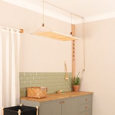 a kitchen with green tiles and wooden counter top next to a plant in a basket