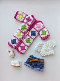 crocheted baby clothes and accessories laid out on a white surface, including an infant's booties