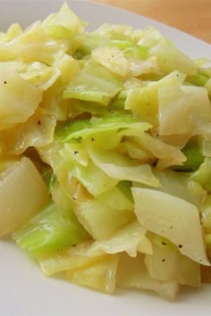 a close up of a plate of food with cabbage and onions on it, next to a fork