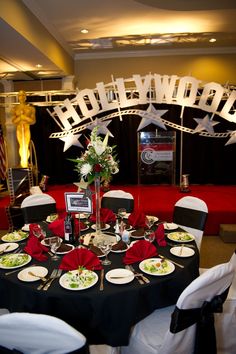 a table set up for an event with black and white linens, red napkins, and silverware