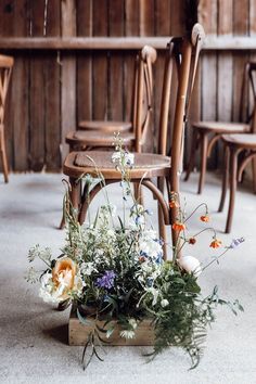 an arrangement of flowers sits on the floor in front of chairs