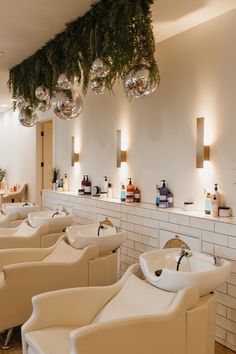 the interior of a hair salon with white chairs and hanging ornaments on the wall above them