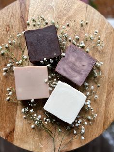 three soap bars sitting on top of a wooden table next to flowers and baby's breath