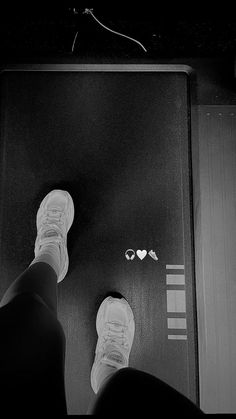 a person standing on top of a black floor next to a pair of white shoes