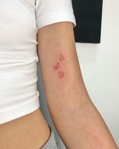 a woman's arm with red ink and butterflies on the back of her arm