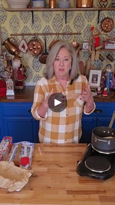 an older woman standing in front of a counter with pots and pans on it