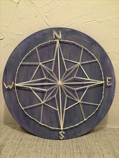 a metal compass sitting on top of a purple plate with white string wrapped around it