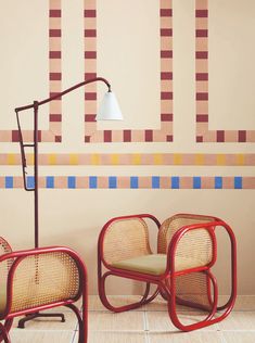 two chairs and a lamp in front of a wall with colorful squares on it,