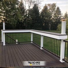 a wooden deck with black iron railings and white posts