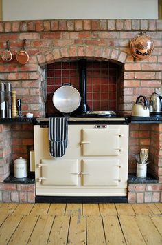 an old fashioned stove with pots and pans on the top shelf next to it