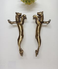 two metal lizards are standing next to each other on a white surface with yellow flowers in the background