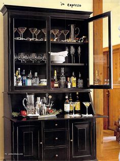 a black china cabinet filled with glasses and bottles