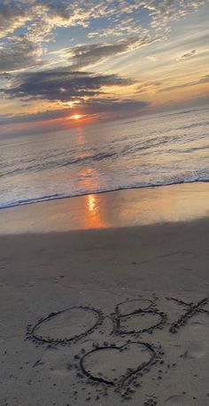 the word love is written in the sand at the beach as the sun goes down