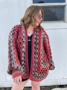 a woman standing in front of a white door wearing a crocheted cardigan