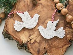 two white doves with red and white striped twine on top of a piece of wood