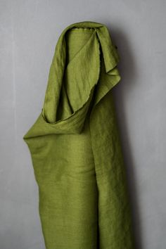 a green cloth hanging on the side of a wall in front of a white wall