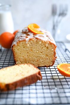 a loaf of orange pound cake sitting on top of a cooling rack next to an orange slice