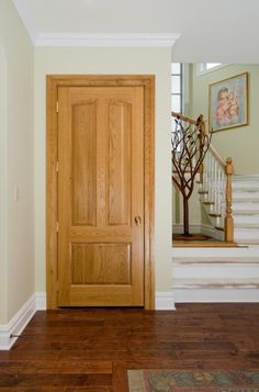 a wooden door in the middle of a room with stairs and framed pictures on the wall