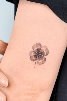 a small four leaf clover tattoo on the side of a woman's thigh,