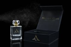 a bottle of perfume sitting next to a black box with gold trimming on it