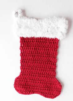 a crocheted christmas stocking hanging on a white wall with a red and white stocking