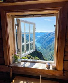 an open window with a view of the mountains and water from it's side