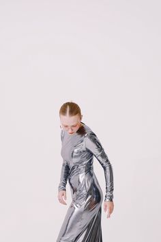 a woman in a silver dress is posing for the camera with her legs spread out