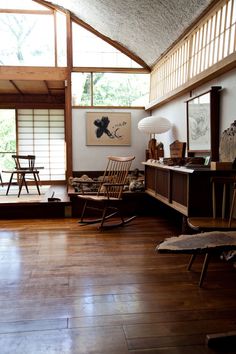 a living room with wooden floors and large windows in it's center wall, along with rocking chairs