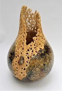 a small vase with intricate designs on the outside and inside, sitting on a white surface