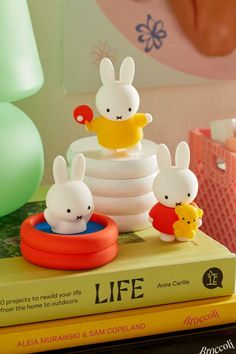 three little bunnies sitting on top of a stack of books next to each other