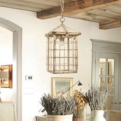 a dining room table with vases and plants on it, hanging from the ceiling