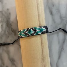 a beaded bracelet sitting on top of a wooden stick