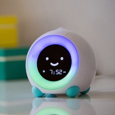 an alarm clock with a smiley face on it's front and back sides, sitting on a table