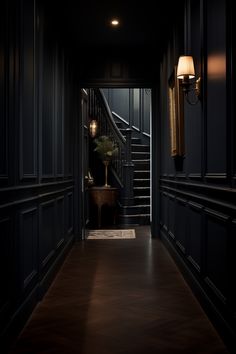 an empty hallway with dark walls and wood flooring is lit by two lamps on either side