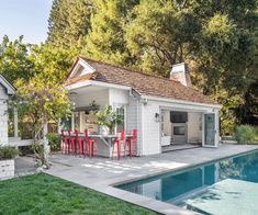 a small pool house with an outdoor kitchen and dining area next to the swimming pool