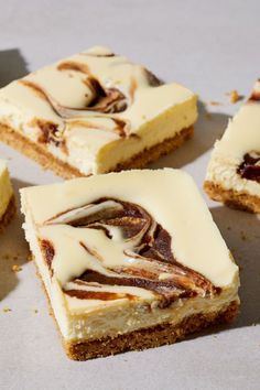 four pieces of cheesecake with white frosting on top and brown swirls in the middle