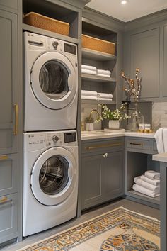 a washer and dryer in a room with gray cabinets, rugs and towels