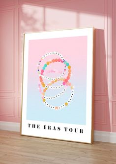 the eras tour poster in front of a pink wall with wooden floor and white frame