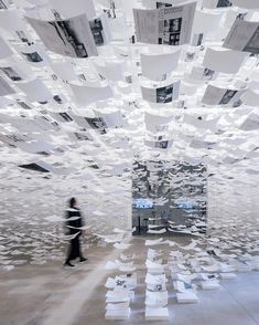 a woman walking through a room filled with lots of papers flying in the air above