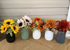 four painted mason jars with sunflowers tied to them on a burlock