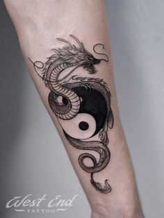 a black and white tattoo with a dragon on it's arm, in the shape of a yin - yang symbol