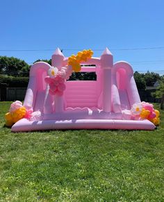 an inflatable pink castle with flowers on the lawn