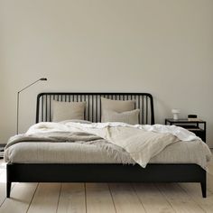 a bed sitting on top of a wooden floor next to a white wall