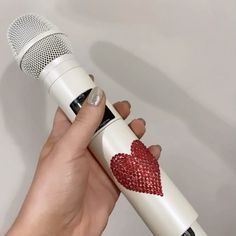 a hand holding a microphone with a red heart on the front and side of it