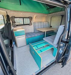 the interior of an rv with blue seats and tables in it's rear door