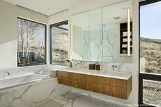 a bathroom with marble counter tops and large windows